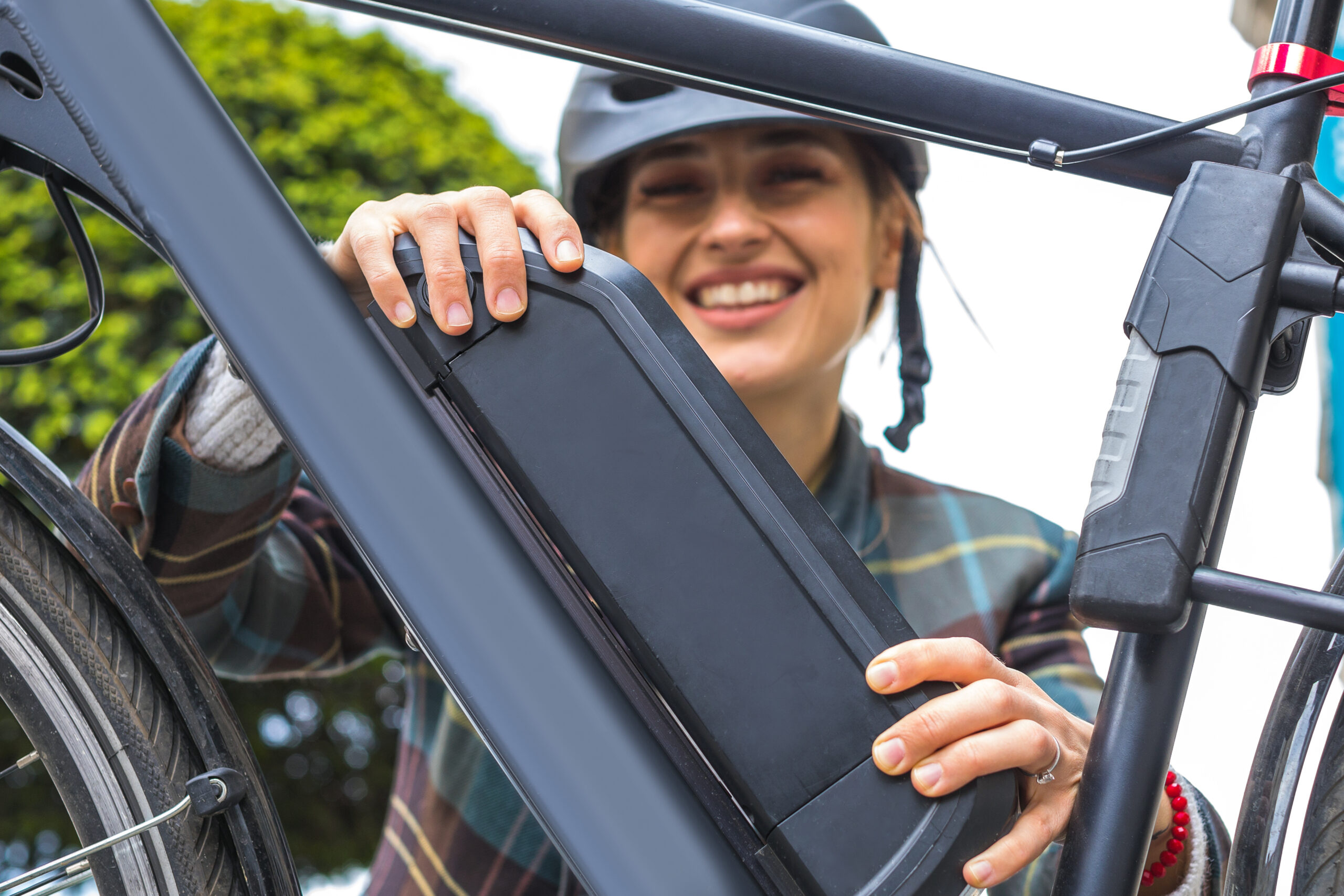 femme tenant une batterie de vélo électrique installée sur le cadre